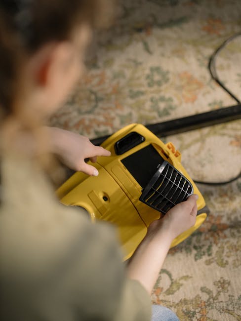 A professional cleaner dressed in full protective gear, including a white suit, gloves, face mask, and shoe covers, is engaged in deep cleaning a beige carpet in a well-lit, modern living room. The cleaner is using a steam or hot water extraction device to sanitize and remove dirt from the carpet's surface, which appears freshly steamed with visible clouds of steam or cleaning foam. The room features a light-colored wooden floor, a white wall with a window allowing natural light to fill the space, and decorative elements such as potted plants, a wooden shelf, and a minimalist aesthetic. This detailed scene illustrates surface cleaning and sanitization processes performed by Carpet Cleaning Lambeth to maintain hygiene and cleanliness in residential environments.
